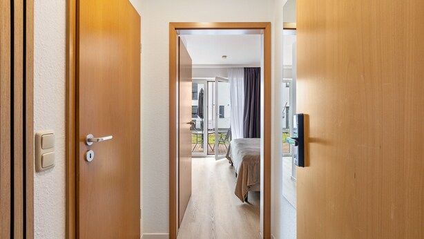 Et hotel med trædøre, en seng og udsigt til det udendørs område.