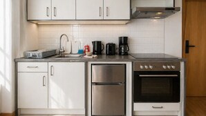 Una cocina moderna con electrodomésticos de acero inoxidable, armarios blancos y salpicadero de azulejos.