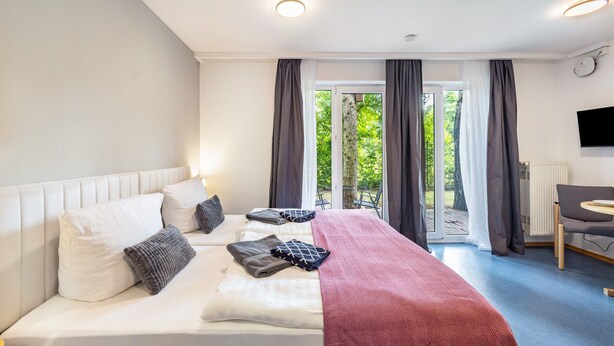 A hotel room with a bed, a desk, and a view of the outdoors. - Apartment '1-1' with Private Terrace, Private Garden and Wi-Fi (Lübeck)