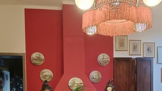 Un comedor con pared roja, una araña y una chimenea.
