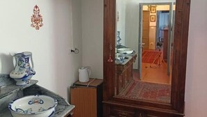 Una habitación con un armario de madera, un televisor en la pared y un espejo grande que refleja un baño.