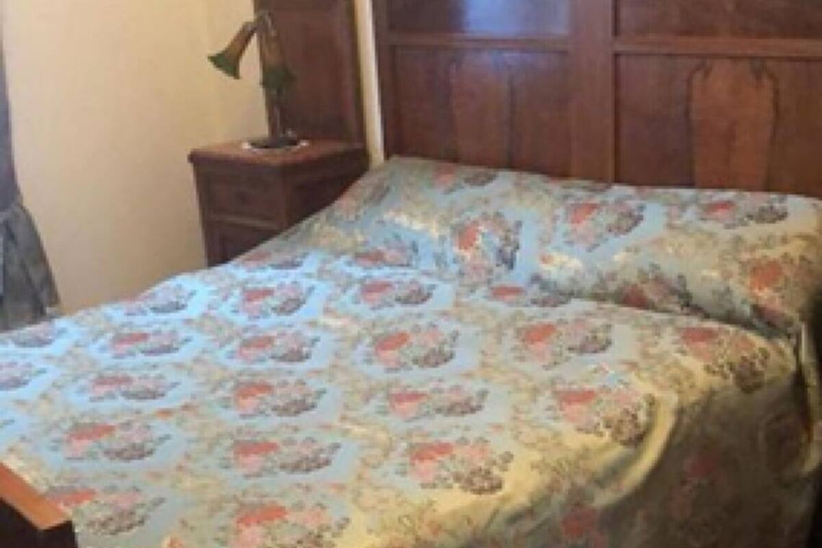 A room with a bed, a nightstand, and a lamp.