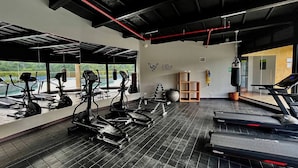 Une salle de sport équipée de tapis de course, de vélos elliptiques et d’un sac de frappe.