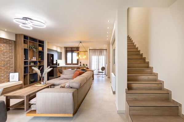 Ein modernes Wohnzimmer mit Sofa, Holzböden, einem Essbereich und einer Treppe.