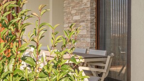 En balkon med stenvæg, et bord, stole og en potteplante.