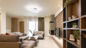 En moderne stue med sofaarrangement, pejs og indbyggede reoler med dekorative genstande.