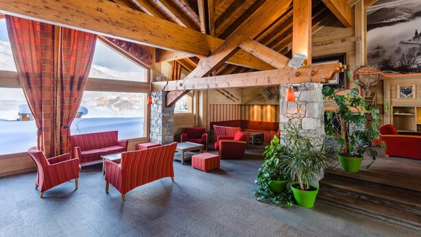 Ein Holzinterieur mit roter Möbel, Steinwänden und Blick auf die Berge.