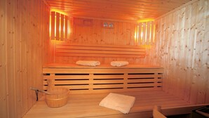 Eine Sauna mit Holzbänken, einem Holzfass und Handtüchern.