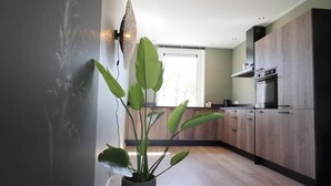 A modern kitchen with wooden cabinets, a built-in oven, and a potted plant.