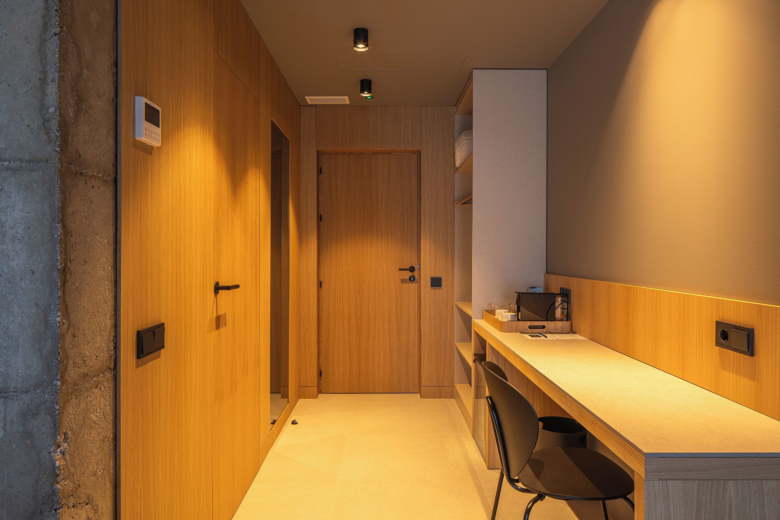Una habitación de hotel moderna con una puerta de madera, un escritorio y una silla.