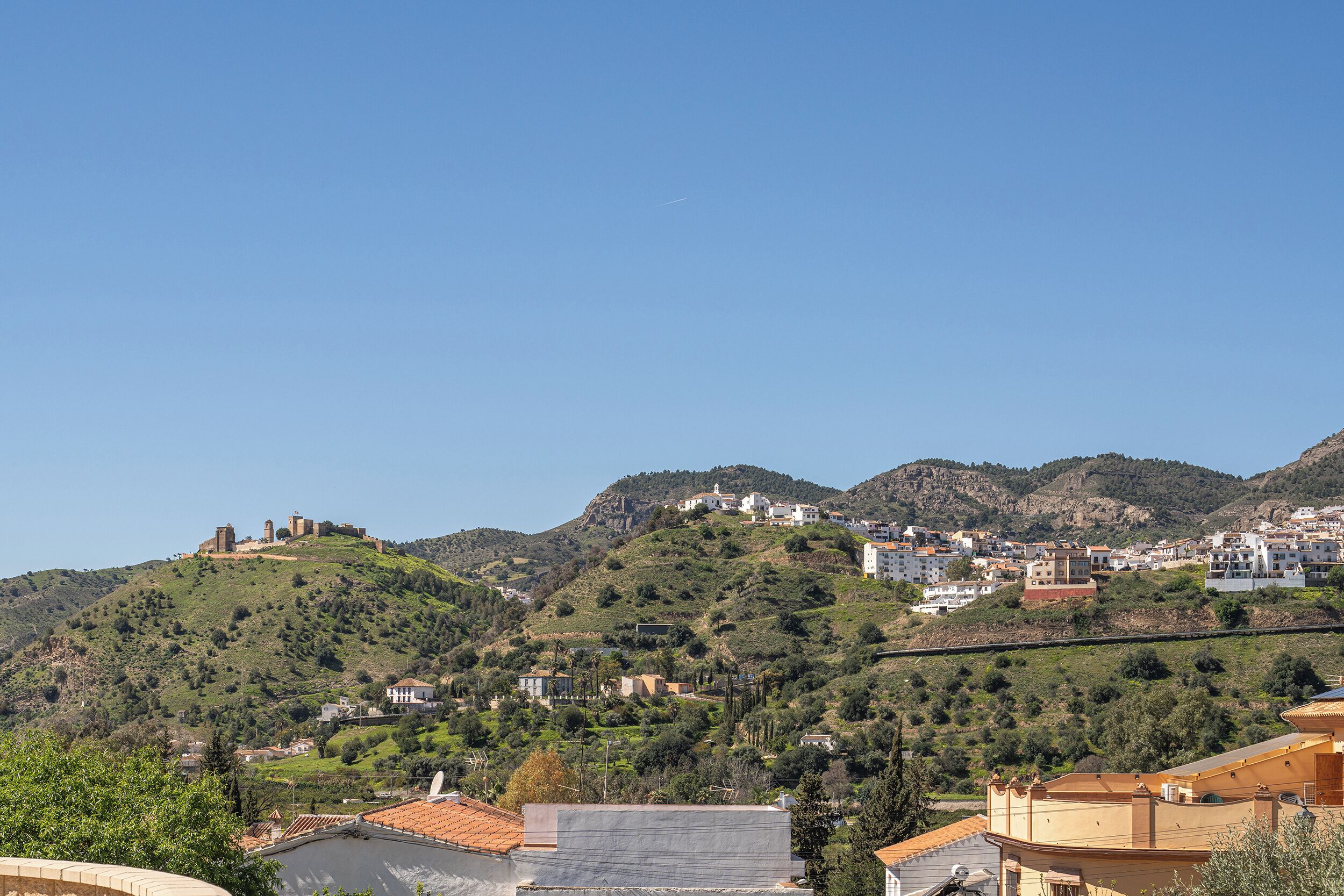 A hillside town with buildings, a prominent castle, and a bridge.