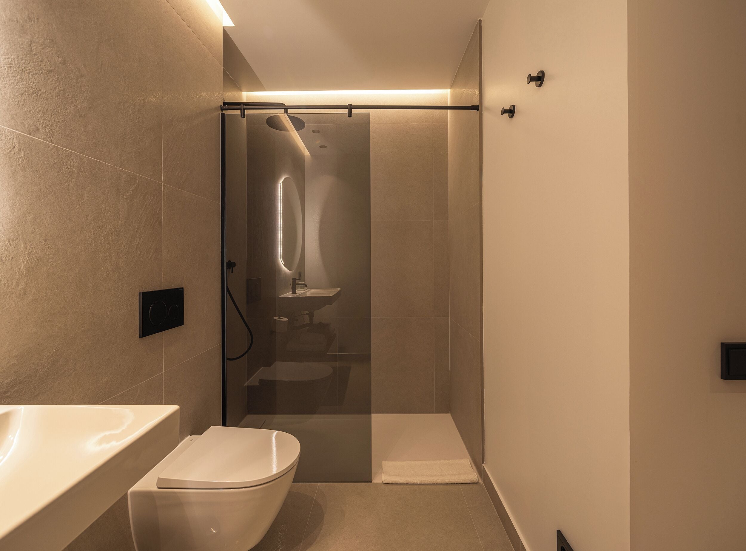 Een moderne badkamer met een douchecabine van glas, een toilet en een wastafel.