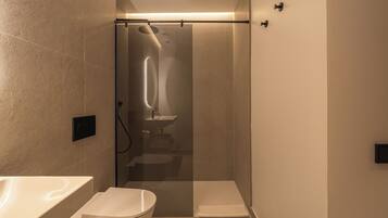 Een moderne badkamer met een douchecabine van glas, een toilet en een wastafel.