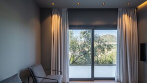 Una camera moderna con un'ampia porta finestra, un divano grigio e un televisore a schermo piatto montato a parete.