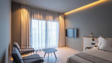 A modern hotel room with a bed, a desk, a chair, and a small table.