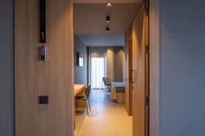 A hotel room with a desk, chair, bed, and a view of the outside through a window. - The Alma Suite (Álora)