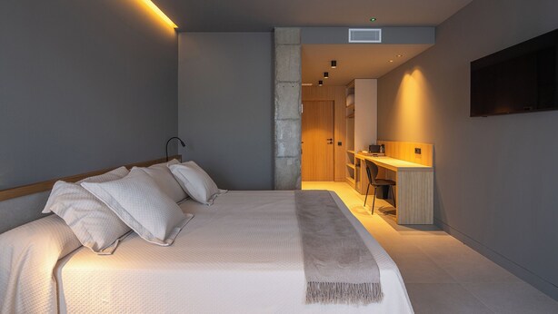 Una camera da letto moderna con un letto, comodini, una scrivania e una sedia.