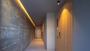 Un corridoio con parete in cemento, pannelli in legno e illuminazione a incasso.