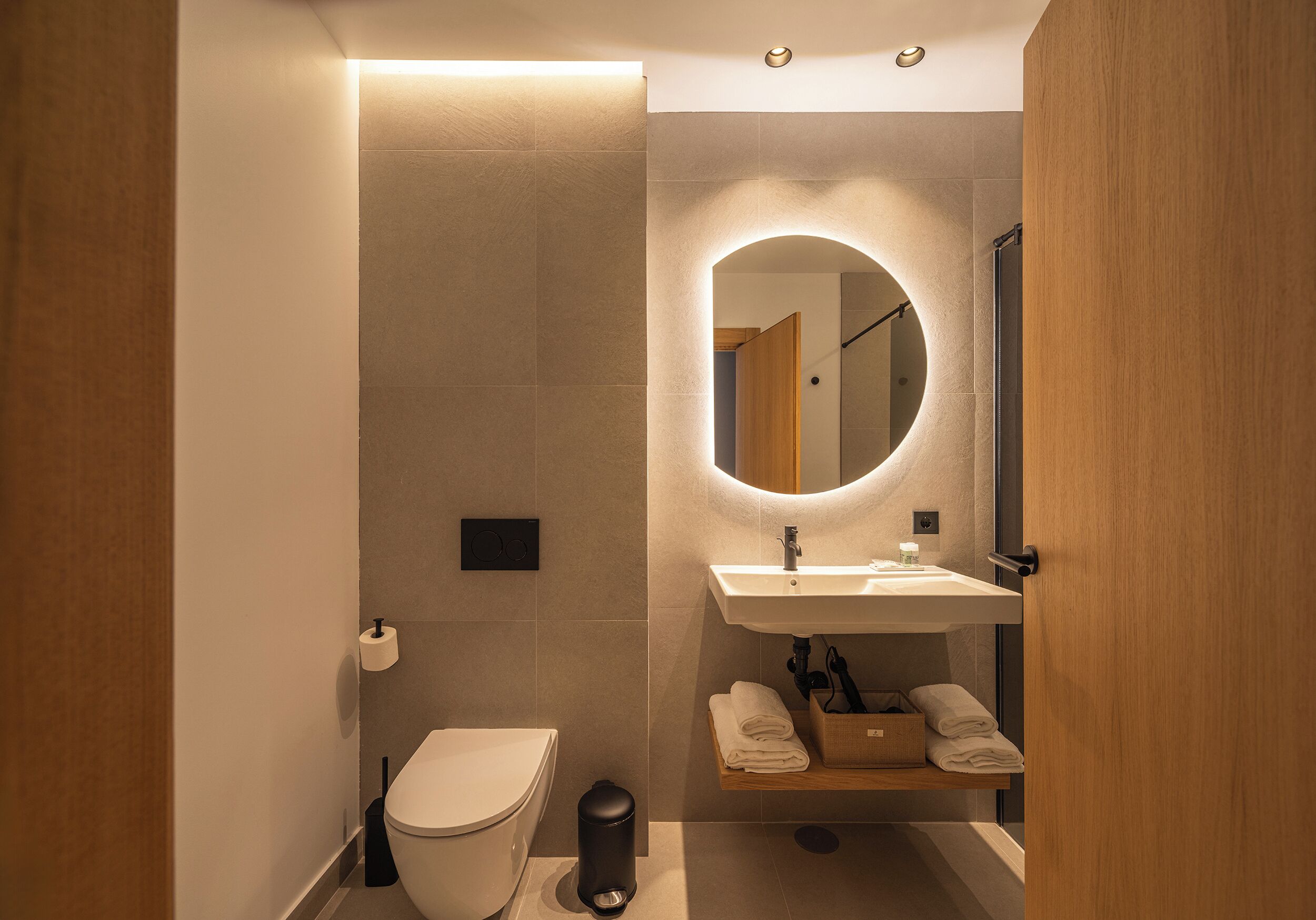 A modern bathroom with a toilet, sink, mirror, and towel rack.