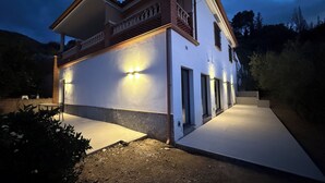 Una casa a due piani con un balcone, illuminazione esterna e vialetto lastricato.