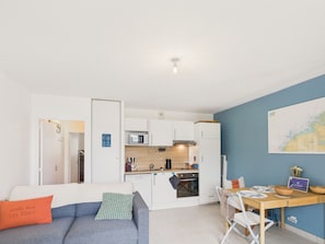 A compact living space with a kitchenette, a dining area, and a sofa with a pillow.
