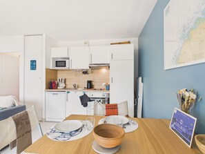 Una cocina compacta con armarios blancos, un microondas y una cafetera.