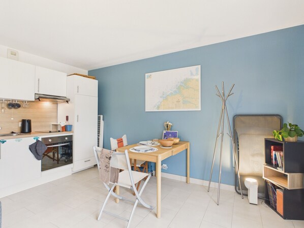 Una cocina moderna con armarios blancos, una mesa de comedor con sillas, un mapa en la pared y una estantería llena de libros.