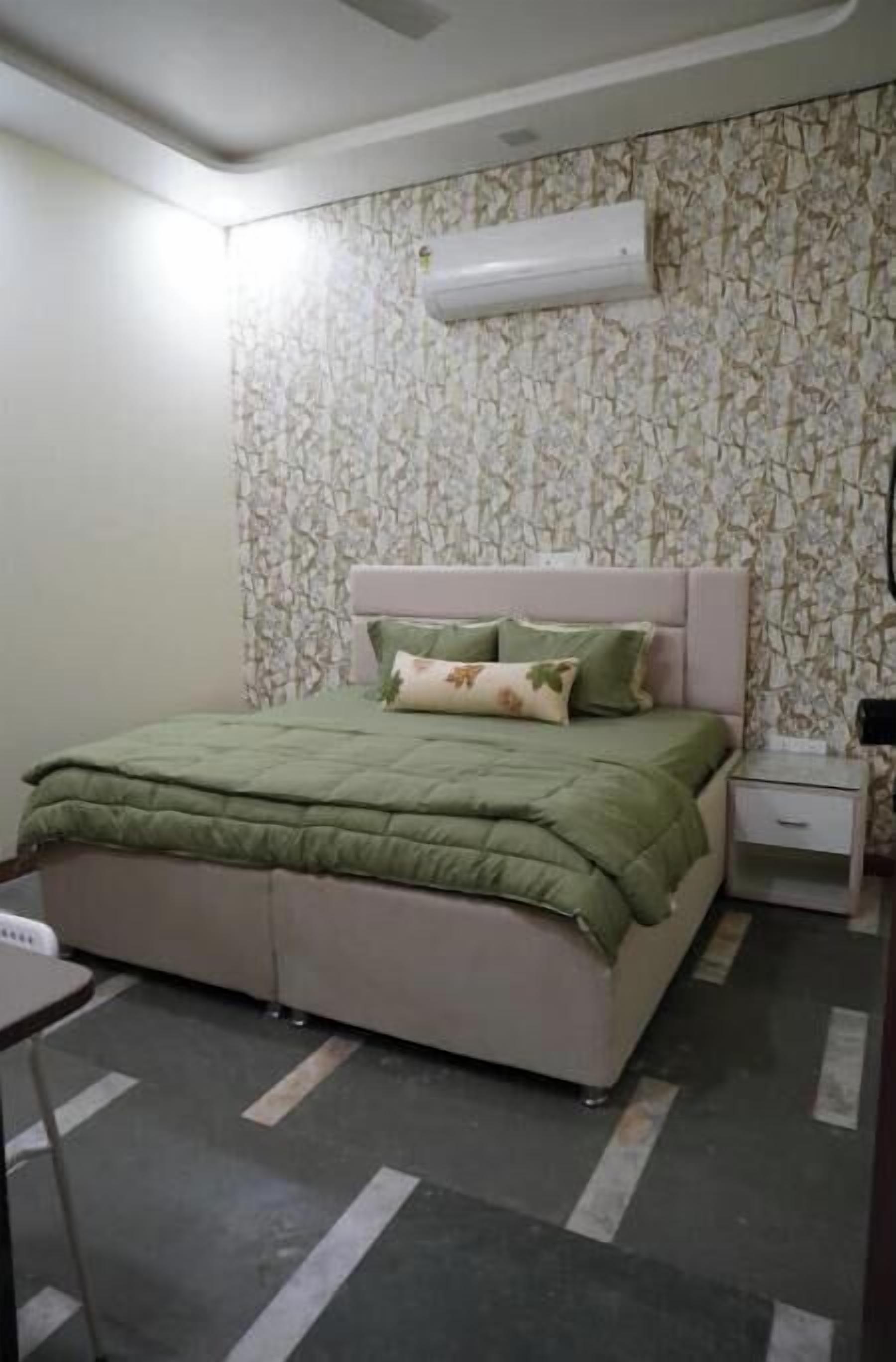 A bedroom with a bed, a nightstand, a chair, and a patterned wall.