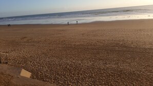 Una playa con arena, algunas personas y el océano.