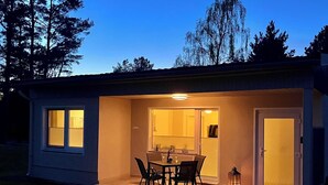 A small, single-story building with a patio area featuring a table and chairs, a door, and a window. - A Cozy Getaway in the Countryside — 2 Bedrooms & a Fireplace (Pruchten)