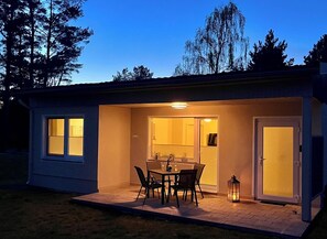 A small, single-story building with a patio area featuring a table and chairs, a door, and a window. - Time out near the Baltic Sea - tastefully furnished, with terrace & wood-burning stove (Pruchten)