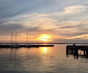A sunset over a calm body of water with boats docked at a pier. - Time out near the Baltic Sea - tastefully furnished, with terrace & wood-burning stove (Pruchten)