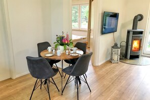 Ein Essbereich mit einem runden Tisch, vier Stühlen, einem Blumenstrauß und einem Kamin.