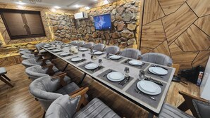 Un salón de conferencias con una larga mesa dispuesta para una reunión, rodeado de sillas tapizadas en gris.