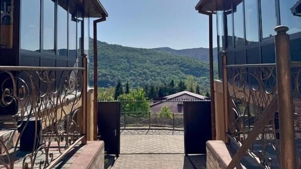 Una escalera conduce a una terraza con barandas de vidrio y vistas a un paisaje montañoso.