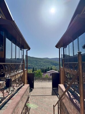 A staircase leading to a terrace with glass railings and a view of a mountainous landscape.