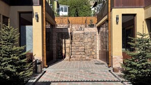 Una entrada de edificio con escaleras de piedra, barandillas de metal y plantas en macetas.