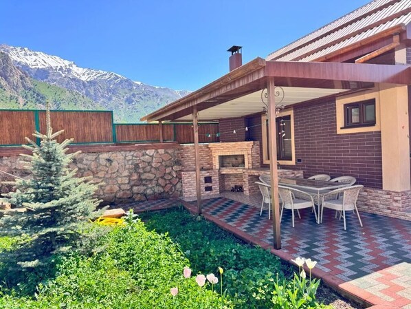 A patio with outdoor furniture, a stone wall, and a view of mountains.