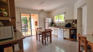 Eine Küche mit Esstisch, Stühlen, einem Kühlschrank, einer Kaffeemaschine und einer Kreidetafel-Speisekarte.