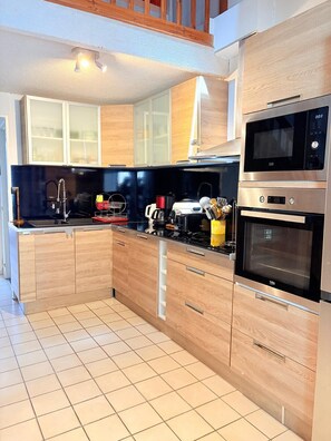 Une cuisine moderne avec des meubles en bois, un four à micro-ondes en acier inoxydable et un four traditionnel.