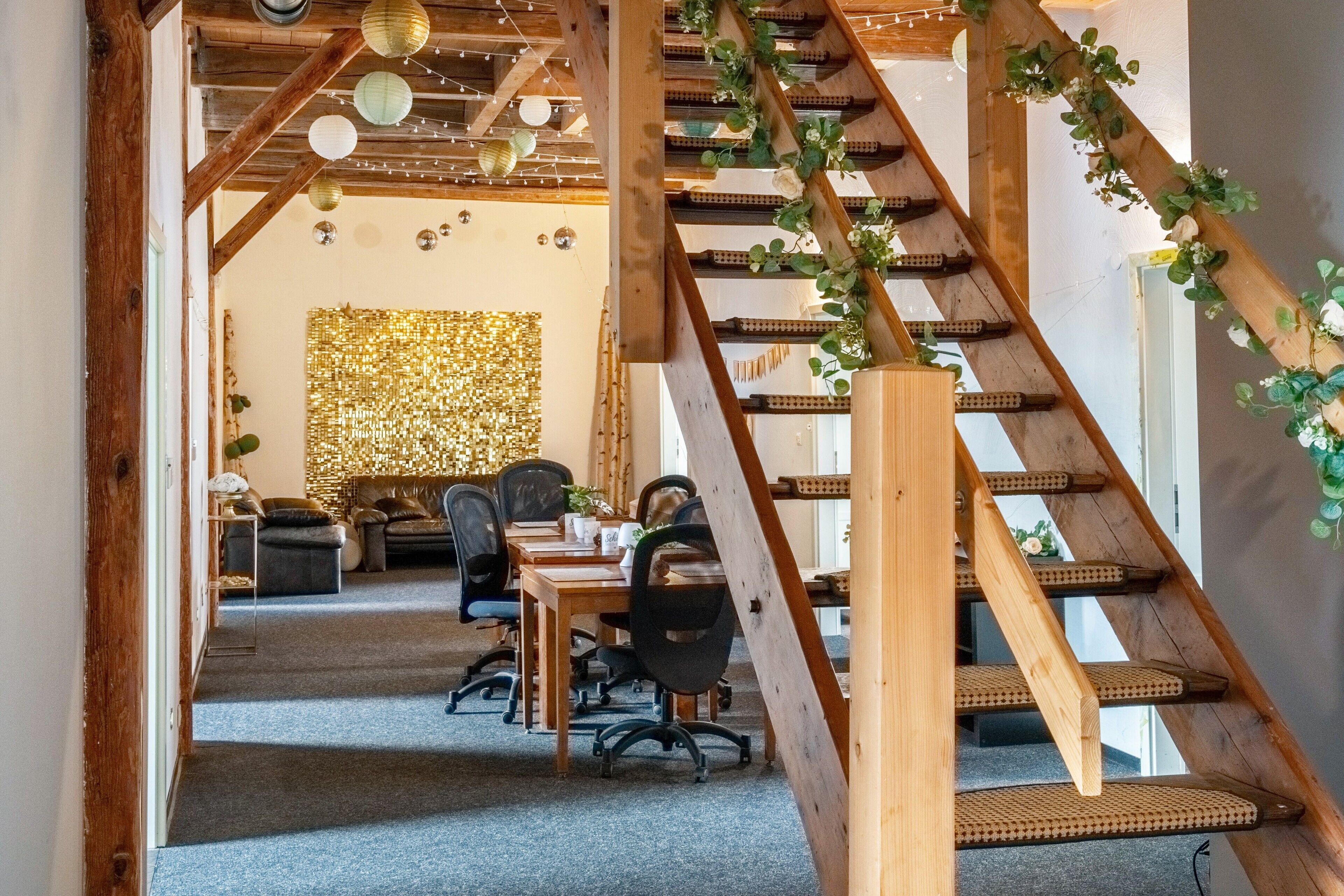 A wooden staircase with a woven seat, leading to a room with a dining table, chairs, and a decorative wall.
