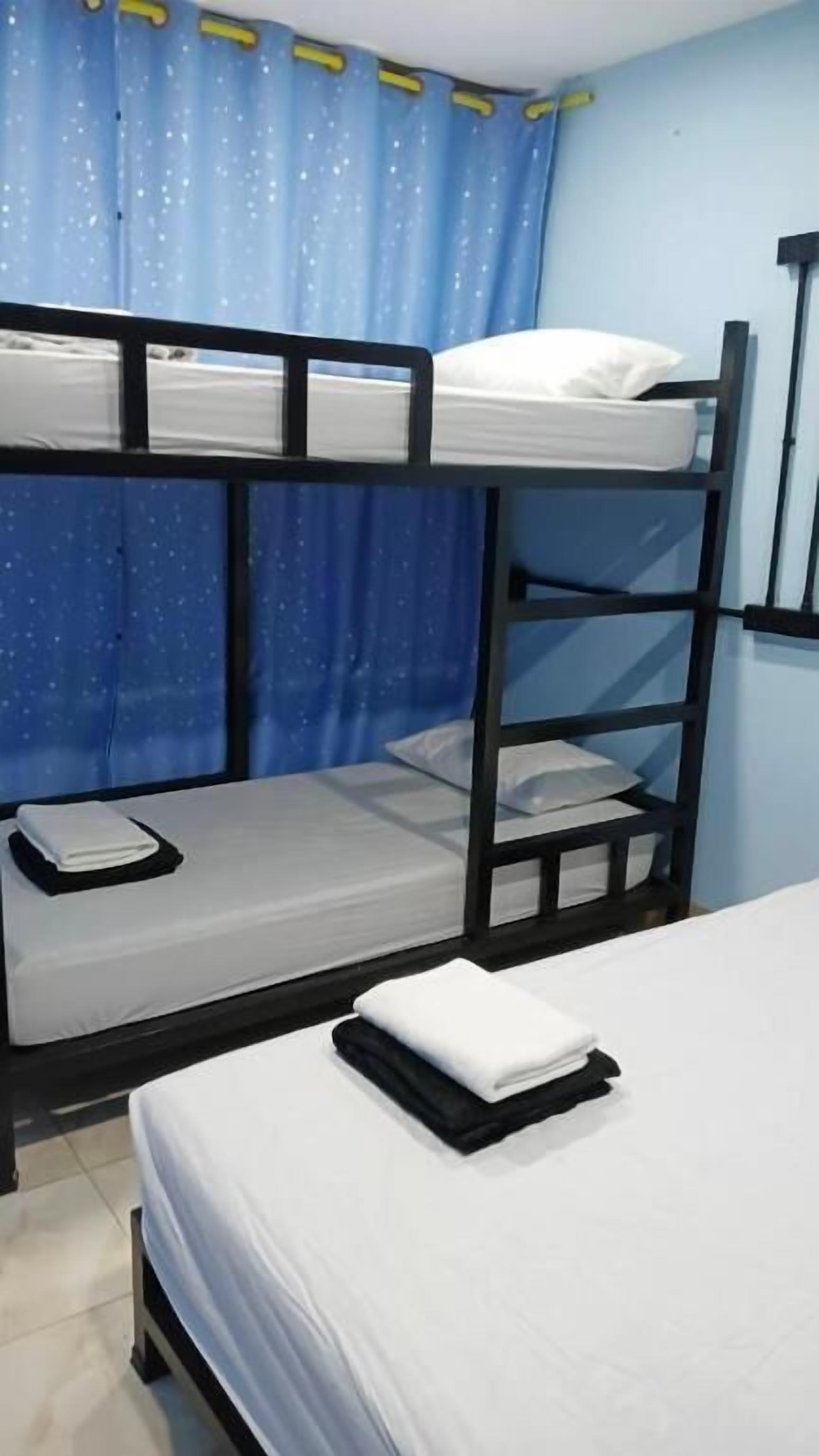 A bunk bed room with a window, curtains, and a bed with a folded towel.