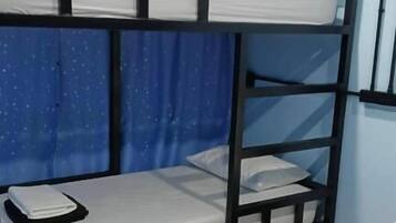 Quarto com beliche, janela, cortinas e cama com toalha dobrada.