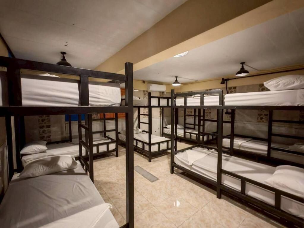 A dormitory room with bunk beds, a ceiling fan, and a tiled floor.