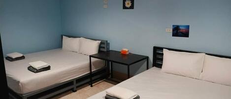 A room with two beds, a small table, and a wall-mounted air conditioner.