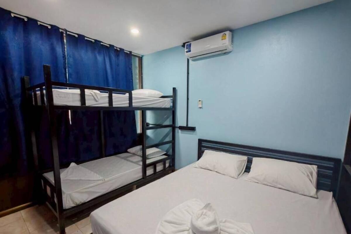 A room with bunk beds, a single bed, and an air conditioning unit.