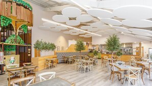 A spacious restaurant with round tables and chairs, a wooden counter, and a children's play area. - Pine Lodge Spa Pet (Thirsk)