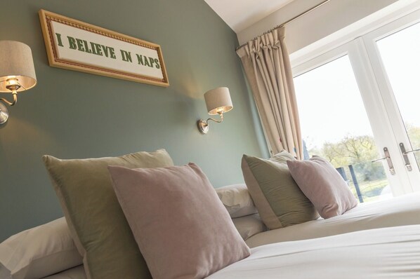 A bedroom with a bed, pillows, a wall-mounted sign, and a window with curtains.