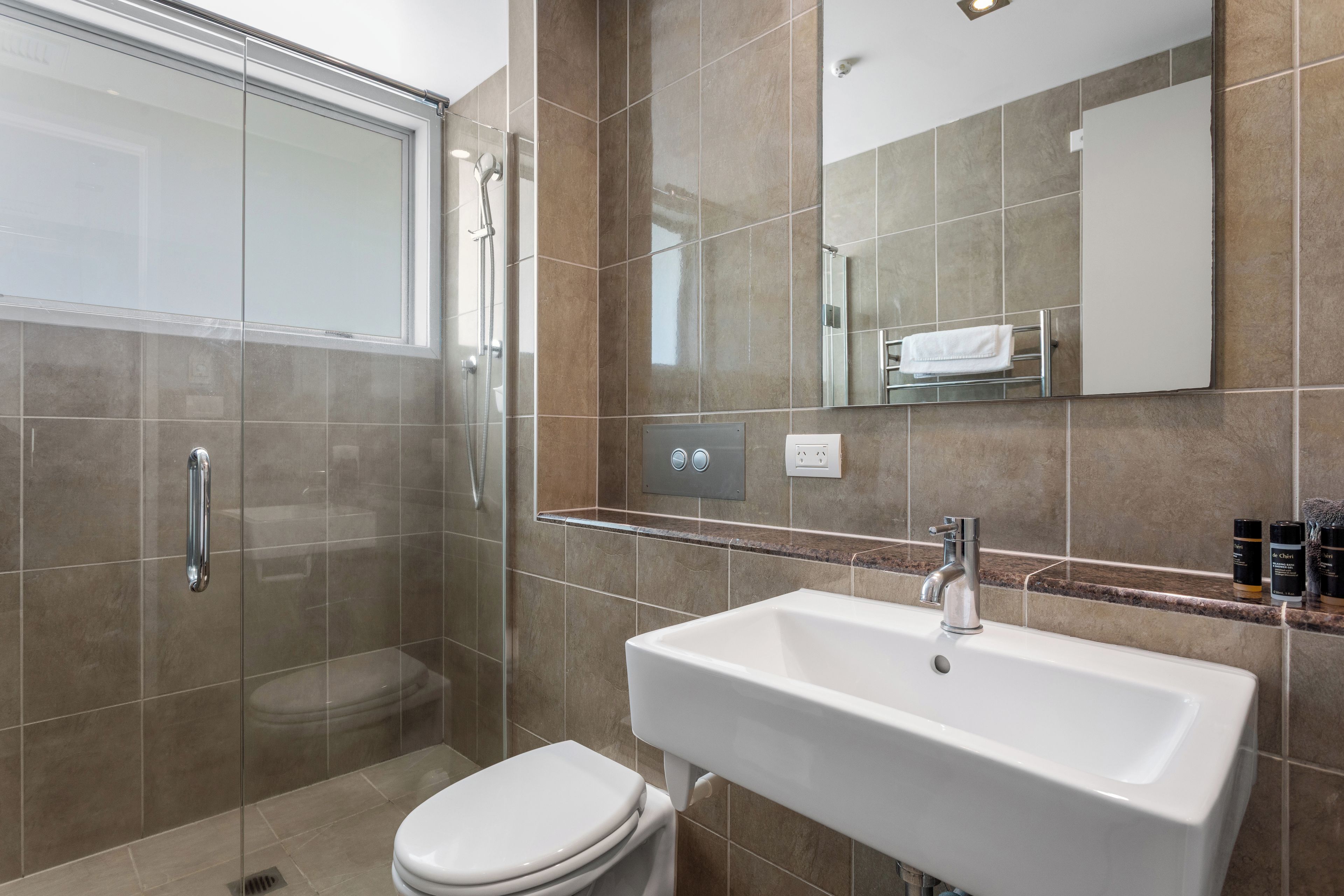 A modern bathroom with a glass shower enclosure, a white sink, and a toilet.
