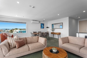 A modern living room with two sofas, a dining table, and a view of the outside.